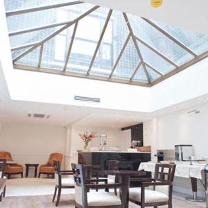 a room with tables and chairs and a large skylight at The Villa Kensington in London