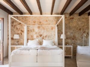 a bedroom with a white bed and a stone wall at VILLA ALENAR - Marratxi- Mallorca in La Cabaneta