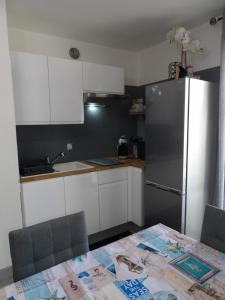 eine Küche mit einem Kühlschrank, weißen Schränken und einem Tisch in der Unterkunft Appartement T2 à 2 pas de la mer de St Cyprien in Saint-Cyprien