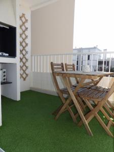 einen Tisch und Stühle auf einem Balkon mit grünem Teppich in der Unterkunft Appartement T2 à 2 pas de la mer de St Cyprien in Saint-Cyprien