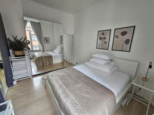 - une chambre blanche avec un grand lit et un miroir dans l'établissement Cosy studio center of Bruxelles, à Bruxelles