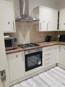 a kitchen with white cabinets and a stove top oven at Large Double Room Private Bathroom And SmartTV 8 in Barking