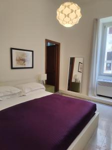 a bedroom with a bed with a purple blanket at AcB Vaticano Suites in Rome