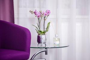 une table en verre avec un vase de fleurs et une chaise violette dans l'établissement Hotel Nikolai Residence, à Berlin