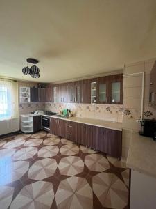 a large kitchen with wooden cabinets and a tile floor at Pensiunea Matis Mărișel in Mărişel