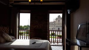 a bedroom with a bed and a balcony with a building at Hostal Medievo in Monforte de Lemos