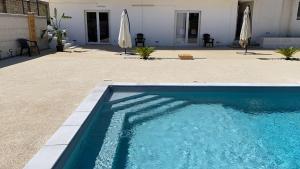 ein Pool neben einem Haus mit Sonnenschirm in der Unterkunft Isabella's Houses in Punta Braccetto