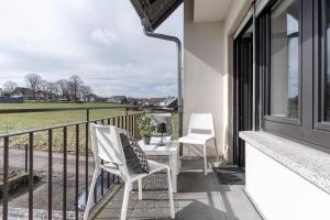 two chairs on a balcony with a view of a field at Moderne Ferienwohnung / Monteurswohnung mit 6 Betten in Driedorf/Herborn in Driedorf