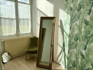 espejo en una habitación con silla y ventana en Gîte Exotique château de la Pervenchère en Casson