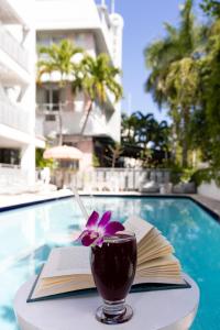 a book and a drink on a table next to a pool at Crest Hotel Suites in Miami Beach