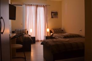 Pokój hotelowy z 2 łóżkami, biurkiem i telewizorem w obiekcie Rooms Guardian w Medziugorie