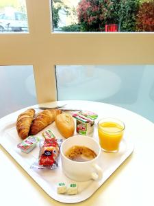 a plate of breakfast food with a cup of coffee and croissants at Premiere Classe Saint Brice Sous Foret in Saint-Brice-sous-Forêt