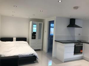 a white bedroom with a bed and a kitchen at Garden studio in Golders Green