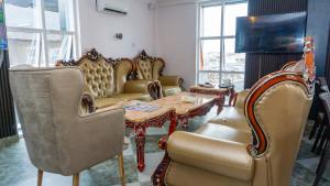 ein Wohnzimmer mit einem Tisch und Stühlen sowie einem Tisch und einem Tisch in der Unterkunft California Luxury Hotel & Suite in Ibadan