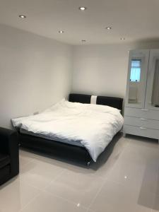 a white bedroom with a bed and a window at Garden studio in Golders Green