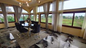 a dining room with a table and chairs and windows at Gaïa Luxury Suites in Libreville