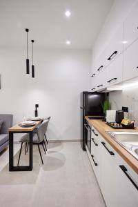 Vasilicari Apartments في خيوس: مطبخ مع دواليب بيضاء وطاولة مع كراسي