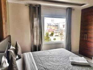 ein Schlafzimmer mit einem Bett und einem großen Fenster in der Unterkunft Hotel Delhi Aerocity, NH 8 in Neu-Delhi