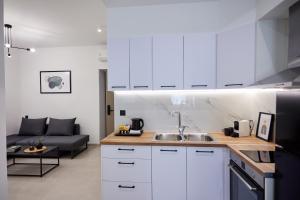 a kitchen with white cabinets and a living room at Vasilicari Apartments in Chios