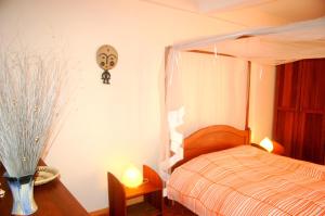 1 dormitorio con 1 cama y un jarrón sobre una mesa en Villa Belle Vue, en Kigali