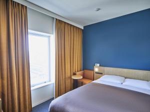 a hotel room with a bed and a window at Kansai Airport Washington Hotel in Izumi-Sano