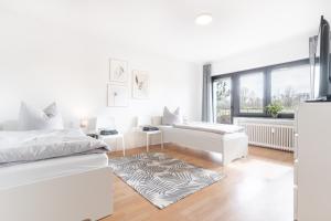 Moderne Ferienwohnung / Monteurswohnung mit 6 Betten in Driedorf/Herborn في Driedorf: غرفة نوم بيضاء مع سرير وأريكة