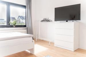 1 dormitorio blanco con TV en una cómoda blanca en Moderne Ferienwohnung / Monteurswohnung mit 6 Betten in Driedorf/Herborn, en Driedorf