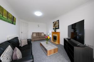a living room with a black couch and a tv at Pure Apartments 2 Bed Duloch - Dunfermline in Fife