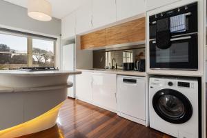 a kitchen with white cabinets and a washer and dryer at Coastal Haven: Modern 3BR Apartment in Vaucluse in Sydney