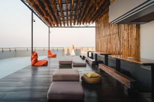 a room with benches and tables and a view of the ocean at THALAY Cha-am by THA in Cha Am