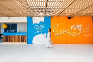 une femme marchant dans une pièce avec un mur orange et bleu dans l'établissement THALAY Cha-am by THA, à Cha Am