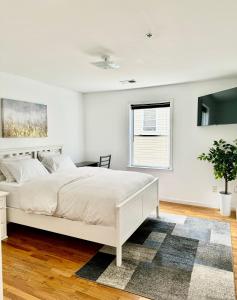 a white bedroom with a white bed and a window at Stylish Evergreen Apartment By Newark Airport in Newark