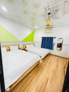 2 camas en una habitación con techos verdes y blancos en Homestay Phúc Lộc Phú Qúy, en Cu Lao Thu