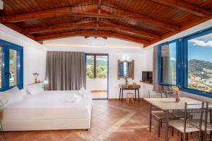 a bedroom with a white bed and a table and chairs at Panorama Studios in Plakias