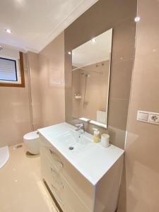 ein Badezimmer mit einem Waschbecken, einem WC und einem Spiegel in der Unterkunft Apartamento muy cerca de la playa in Ribeira