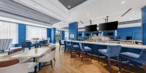 un restaurante con paredes y sillas azules y un bar en Hilton University of Florida Conference Center Gainesville, en Gainesville