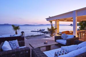 a patio with couches and a table and the ocean at Hippie Chic Hotel in Agios Ioannis Mykonos