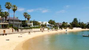 a beach with people and a boat in the water at Coastal Haven: Modern 3BR Apartment in Vaucluse in Sydney