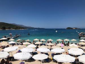 a beach with white umbrellas and people in the water at Seaside Villa Genti Seaview in Ksamil