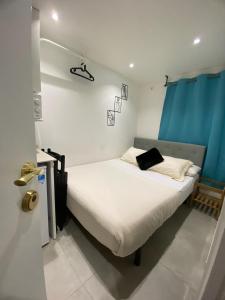 1 dormitorio pequeño con 1 cama con sábanas blancas y cortinas azules en Suites con baño privado frente a la estación de metro L5 Fira Barcelona, en Hospitalet de Llobregat