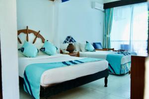 um quarto com 2 camas com lençóis azuis e brancos em Plaza Beach Hotel em Bamburi
