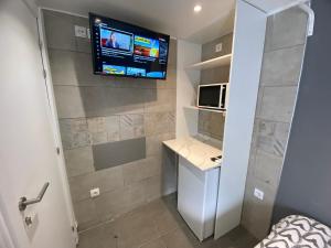 baño pequeño con TV en la pared en Suites con baño privado frente a la estación de metro L5 Fira Barcelona, en Hospitalet de Llobregat