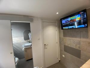 Habitación con baño y TV en la pared. en Suites con baño privado frente a la estación de metro L5 Fira Barcelona, en Hospitalet de Llobregat