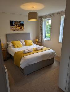 a bedroom with a large bed with yellow pillows at Two Bedroom Lodge In The Country - Oak, Stag, Acorn in Liskeard