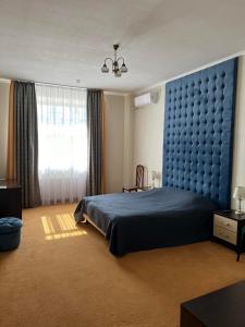 a bedroom with a blue bed with a blue headboard at In hotel in Kamianets-Podilskyi