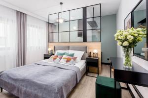 Un dormitorio con una cama y un escritorio con un jarrón de flores en Rent like home - Apartamenty DEO PLAZA, en Gdansk