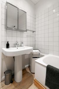 a white bathroom with a sink and a tub at Stylish Flat with Artistic Flair in Central London in London