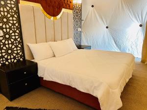 a bedroom with a large bed with a white comforter at Shaheen Camp Wadi rum in Wadi Rum