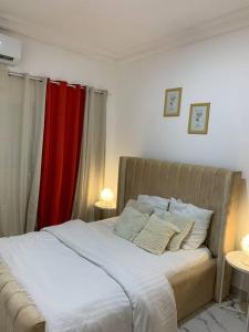 a bedroom with a large bed with a red curtain at Le bien être in Libreville