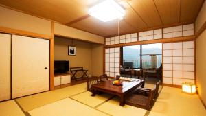 a living room with a table and chairs and a television at 海悦温泉ホテル in Miyanoshita